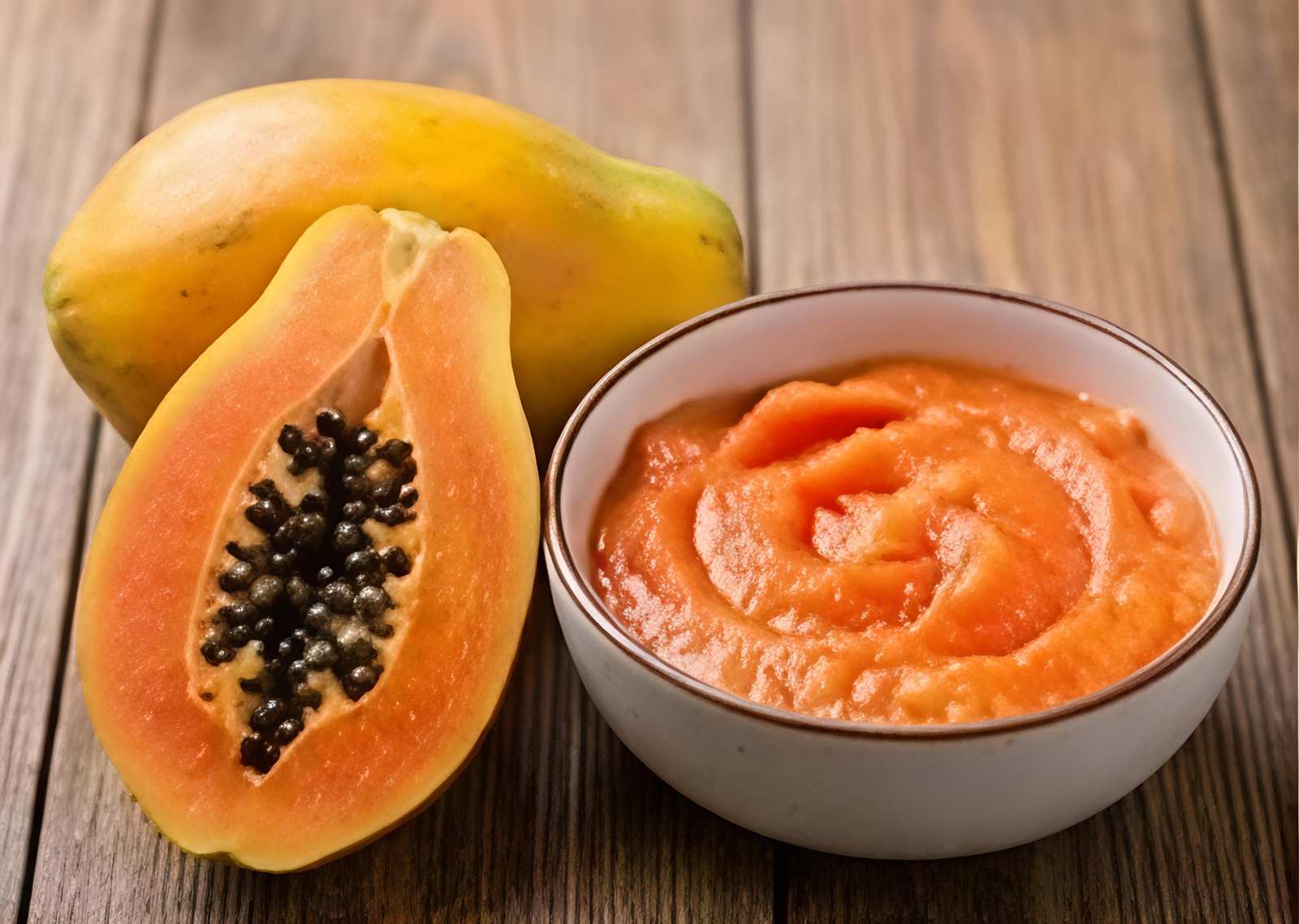 Bowl of papaya pulp from India with a whole and a halved papaya